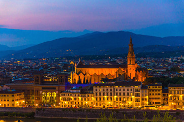 Top aerial evening view of Florence city with Basilica di Santa Croce, city buildings lights and hills at night dusk twilight, Tuscany, Italy