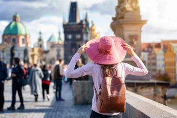 Touristin mit Hut und Rucksack steht auf der Karlsbrücke in Prag während eines Sightseeing Trips
