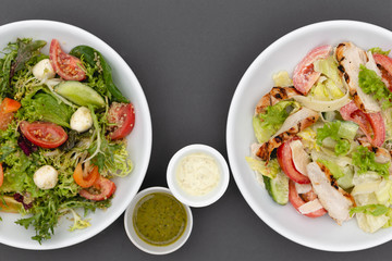 white deep plates with fresh salad ingredients mixed with sauce placed on an attractive background. A place for a menu, banner or advertisement