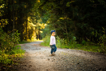 Portrait of 2 years old baby girl in forest walking by herself. Not wanting to follow parents.