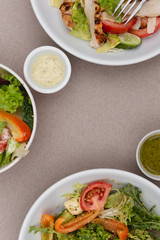 white deep plates with fresh salad ingredients mixed with sauce placed on an attractive background. A place for a menu, banner or advertisement