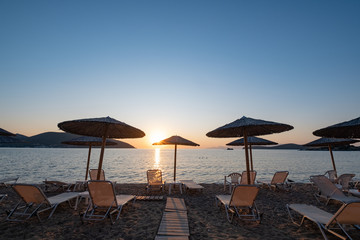 Beach umbrella in the Greece, landscape with beautiful sunrise and summer beach
