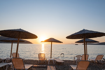 Beach umbrella in the Greece, landscape with beautiful sunrise and summer beach