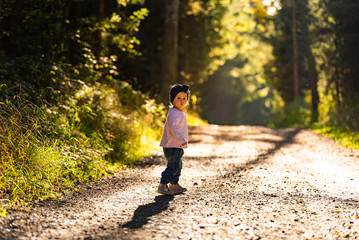 Obraz premium Portrait of 2 years old baby girl in forest walking by herself. Not wanting to follow parents.