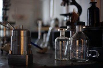 old fashioned retro objects of the twentieth century on the table. Vintage glass bottles, old glass flasks, microscope on background