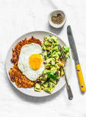 Sweet potato rostis with fried egg and avocado salsa on light background, top view