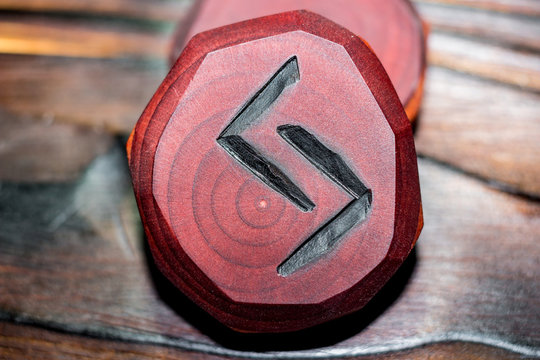 Rune Jera (Jeran, Jeraz)) red color carved from wood on a wooden background - Elder Futhark