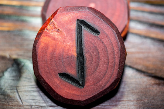 Rune Eihwaz (Eihaz) red color carved from wood on a wooden background - Elder Futhark