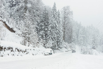 Snowy road in winter with an SUV parked.