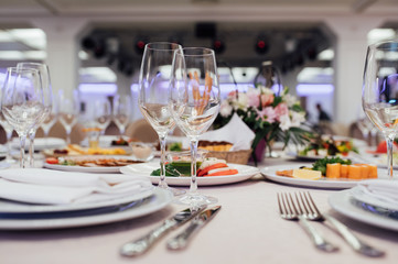 Glasses, flower fork, knife served for dinner in restaurant with cozy interior