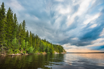 Orange dawn, sunset on the Kama river in cloudy weather, rocky steep Bank overgrown with forest.