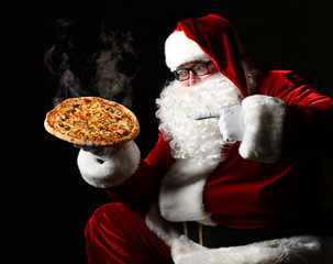 Happy laughing Santa Claus hold big hot steaming original pizza offering pointing finger. New year and Merry Christmas fast food 