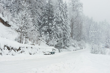 Snowy road in winter with an SUV parked.
