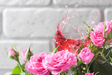 Natural pure rose oil or scented water in bottles for spa, skin care or aromatherapy. Glass bottle on a wooden table, small pink roses with leaves. Organic cosmetics concept.