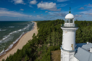 Fototapeta na wymiar White Uzhava lighthouse on the shore of Baltic Sea. Sunny day.