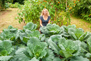 Smiling woman in the vegetable garden savoy cabbage