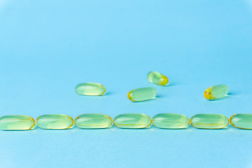 Fish oil (fish fat) capsules. Omega 3 vitamins in yellow gelatin capsules on a blue background