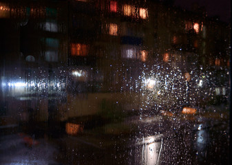 Night rainy sityscape outside the window pane - defocused blurred background