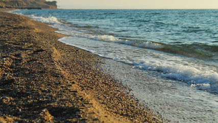 sand pebbles beach small waves seascape at sunset