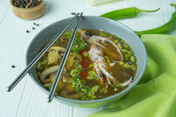 Miso soup with squid, mushrooms and herbs. Seaweed soup. Asian food. White wood background.