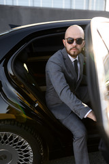 Business man in suit opening black car door
