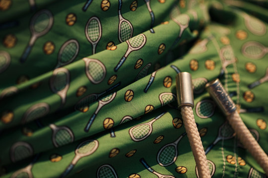 Close up of green bathing man costume with tennis rackets and balls motif
