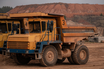 Huge old quarry yellow truck on a quarry background. Big heavy equipment for work in quarries.