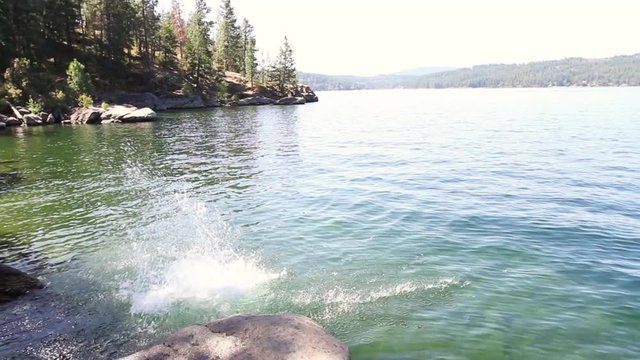 Man Jumping form rocks into Coeur d' Alene Lake from a very well known hiking trail, Tubs Hill