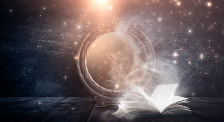An open book and a magic mirror against the backdrop of a night landscape. Abstract dark scene,...