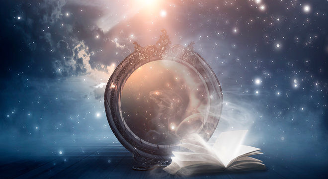 An open book and a magic mirror against the backdrop of a night landscape. Abstract dark scene, mystical background, fantasy.