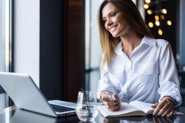 Brunette Business woman working with papers near window in cafe