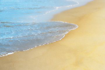 Soft wave of blue sea water on golden sandy beach. Background. Selective focus.