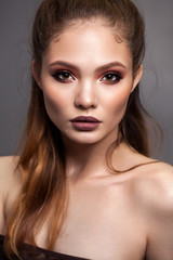 Beautiful young model with evening makeup and sharp cheekbones. Red smoky eyes and matt lips.