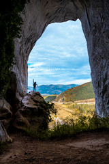 Oñati, Gipuzkoa / Spain »; October 27, 2019: A young woman climbing the ramp of the Aitzulo Eye Cave in Oñati with one arm raised