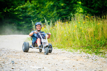 Man enjoying a fast ride go kart downhill in a mountain off road. - obrazy, fototapety, plakaty