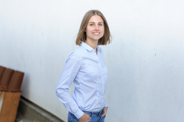 Portrait of a young successful woman working IT company on the background of the white wall