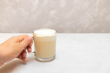 Woman hand holding a cup of cheese tea with green tea and cream cheese foam on grey neutral background