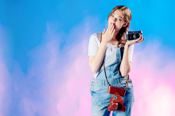 young beautiful girl holding a retro camera on a blue background is going to travel