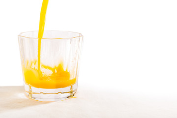 A glass tumbler is being filled with freshly squeezed Florida orange juice.