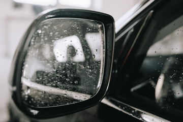 Car mirror covered with water drops