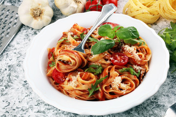 tagliatelle pasta with tomato sauce parmesan basil on rustic background