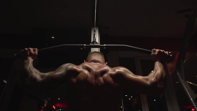 Pulls of fit guy in gym mashine, slow motion, 250fps