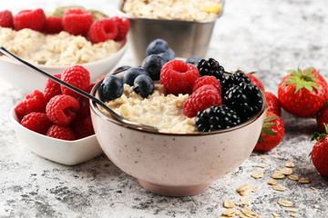 Bowl of oatmeal porridge with banana, raspberries coconut and caramel sauce on rustic table, hot and healthy food for Breakfast