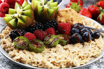 Bowl of oatmeal porridge with banana, raspberries coconut and caramel sauce on rustic table, hot and healthy food for Breakfast