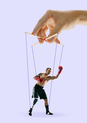 Man like a puppet in somebodies hands on purple background. Concept of unfair manipulation,...