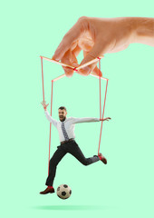 Man like a puppet in somebodies hands on green background. Concept of unfair manipulation,...