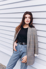 Close up portrait of young hipster modern young brunette girl posing in trendy casual coat on wooden white background. Fashion, modeling, natural beauty concept