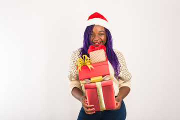 A dark-skinned happy girl holds a lot of red gifts in her hands. The concept of new Year, Christmas gifts, giving, Christmas shopping. Template for your advertising