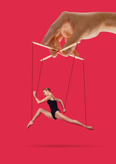 Woman like a puppet in somebodies hands on pink background. Concept of unfair manipulation,...