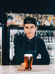 Beer pub Pint of beer Young bartender is holding out a glass of beer at the bar counter